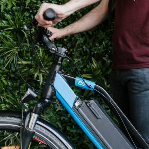 close-up-sideways-cyclist-holding-e-bike-with-green-wall-background